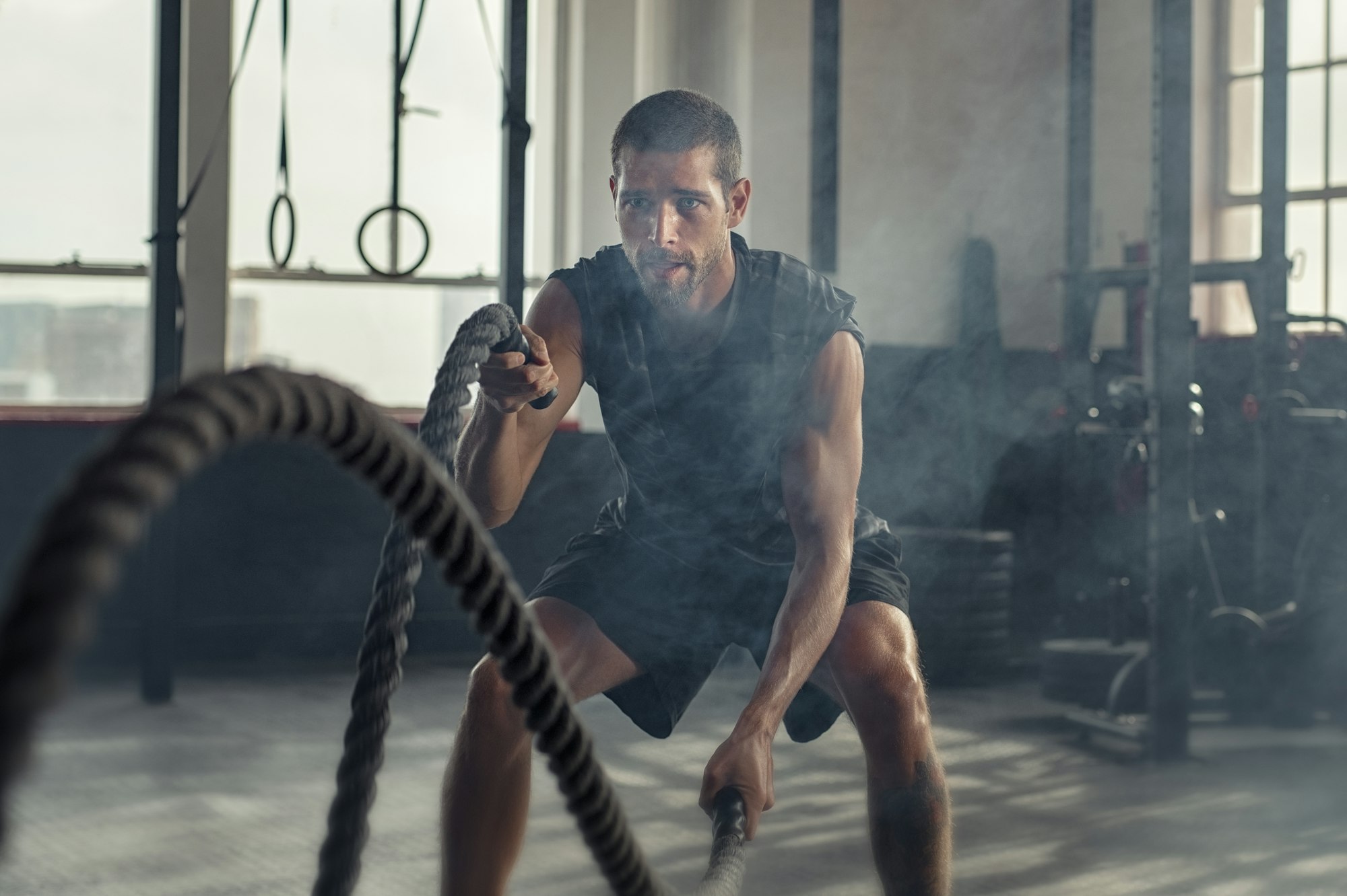 Young man exercising using battle rope